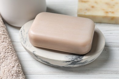 Photo of Dish with soap bar on white wooden table, closeup