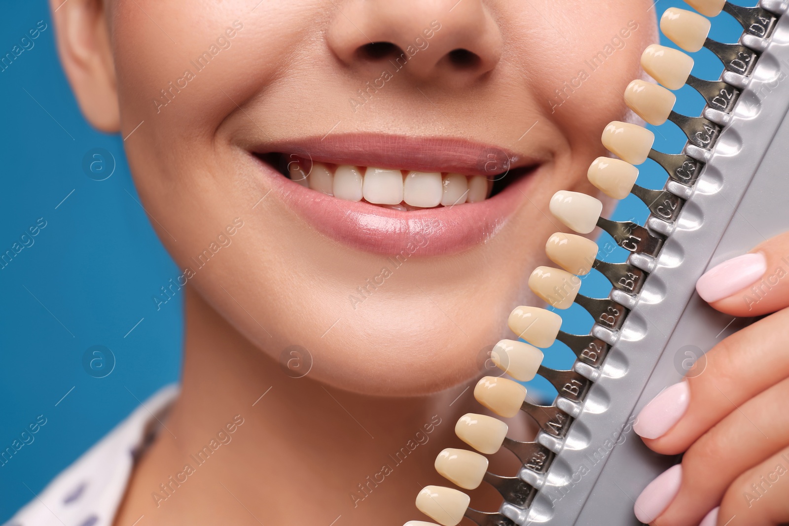 Photo of Woman checking her teeth color on blue background, closeup. Cosmetic dentistry