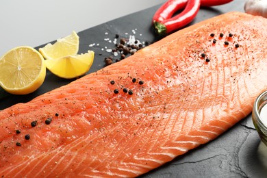 Fresh raw salmon and ingredients for marinade on black table, closeup