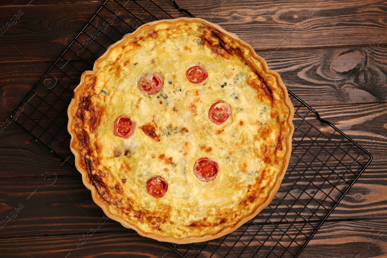 Photo of Delicious quiche with cheese and tomatoes on wooden table, top view