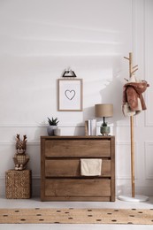 Stylish room interior with wooden chest of drawers near white wall