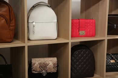 Photo of Collection of stylish woman's bags on wooden shelving unit