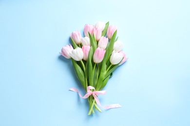 Photo of Beautiful pink spring tulips on light blue background, top view