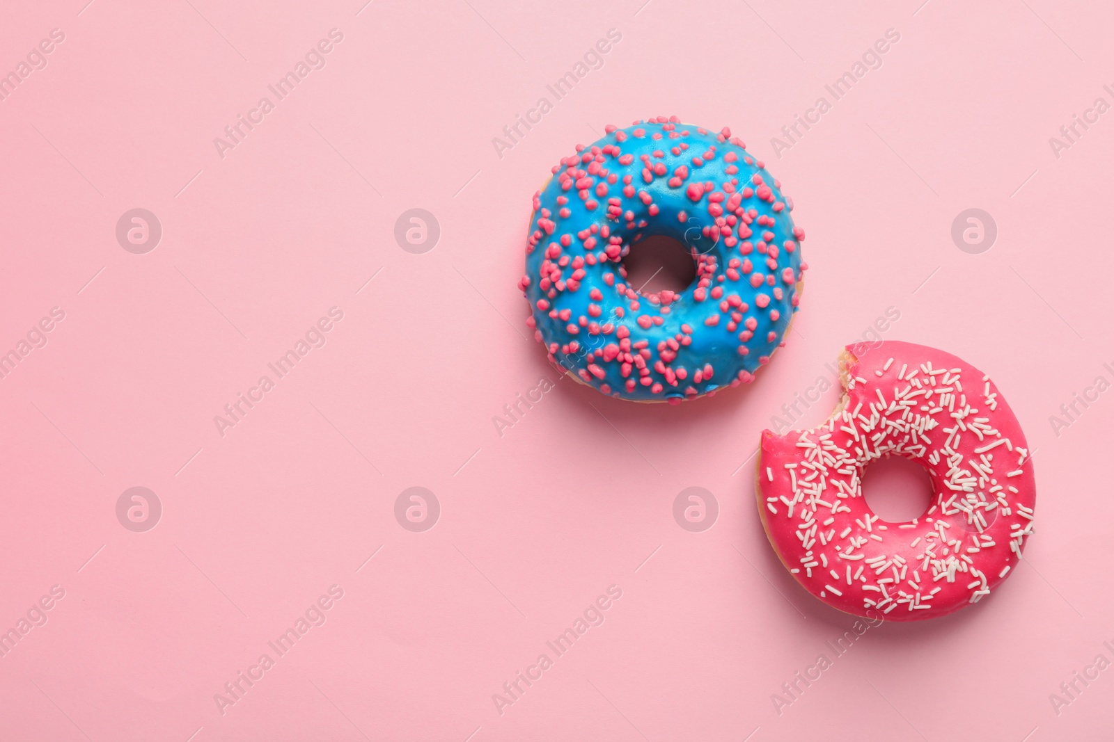 Photo of Delicious glazed doughnuts on color background, top view