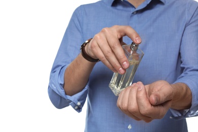 Man applying perfume on wrist against white background, closeup
