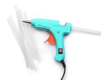 Turquoise glue gun and sticks on white background, top view