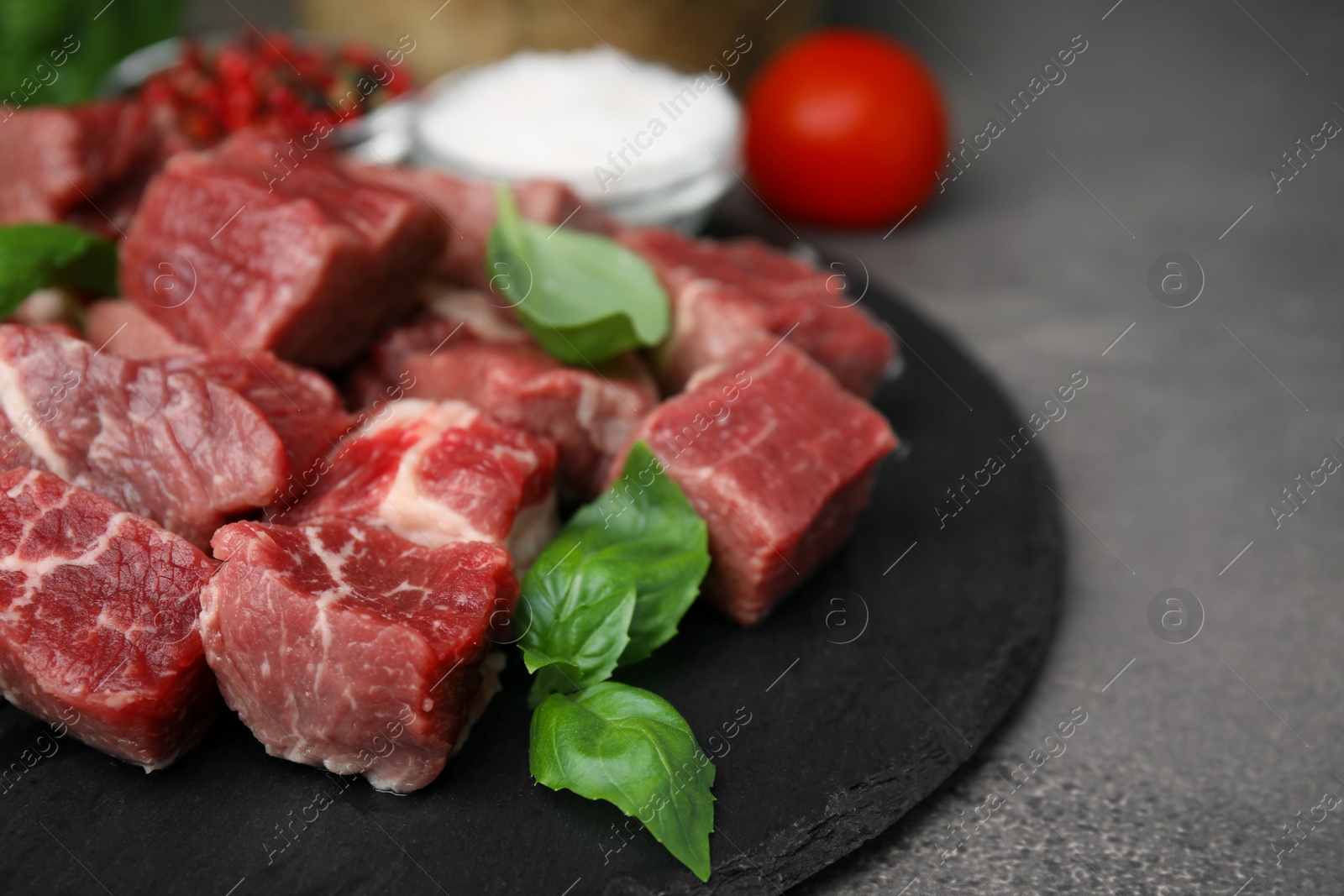 Photo of Cut fresh beef meat and basil leaves on brown table, closeup. Space for text