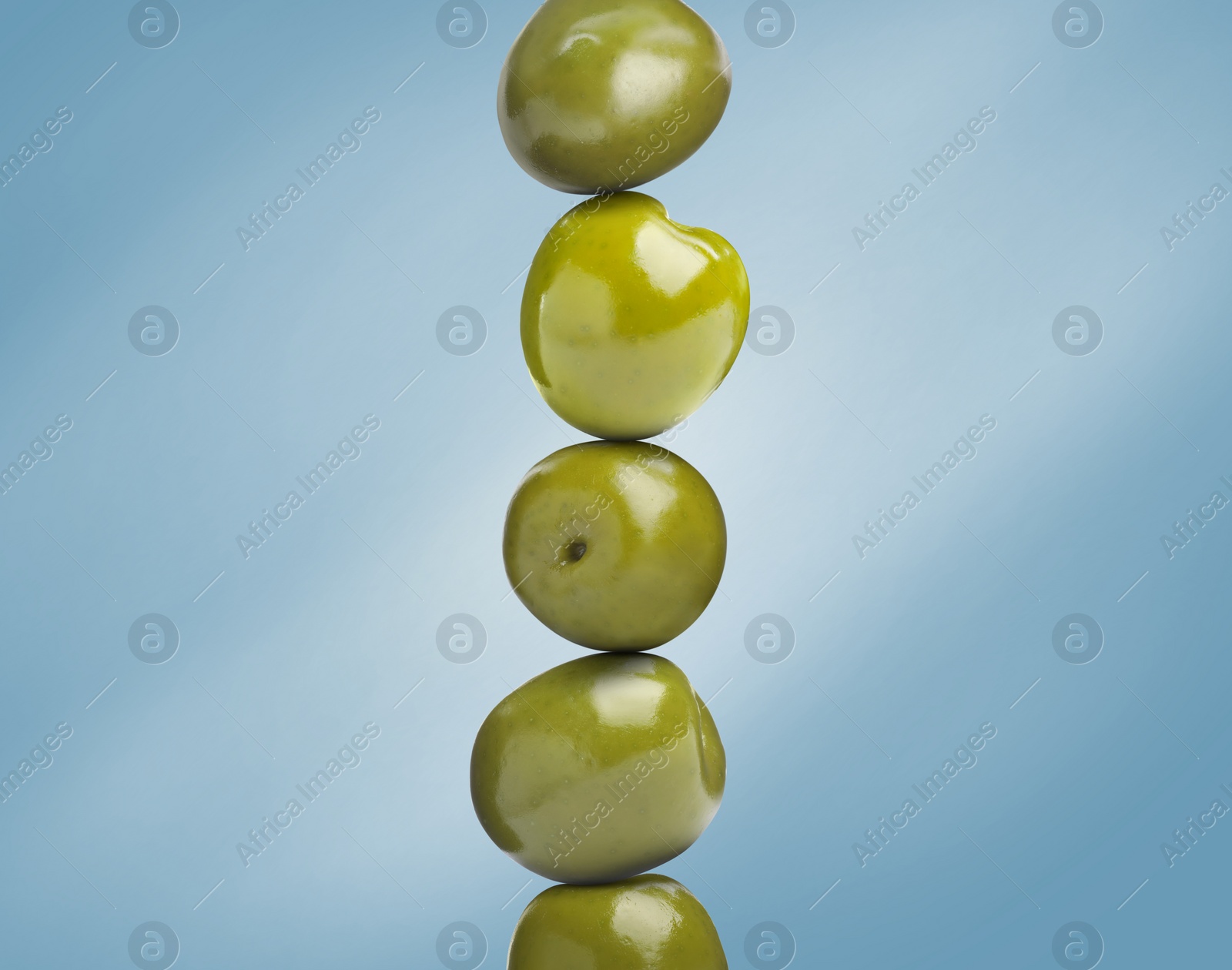 Image of Stack of whole olives on light blue background