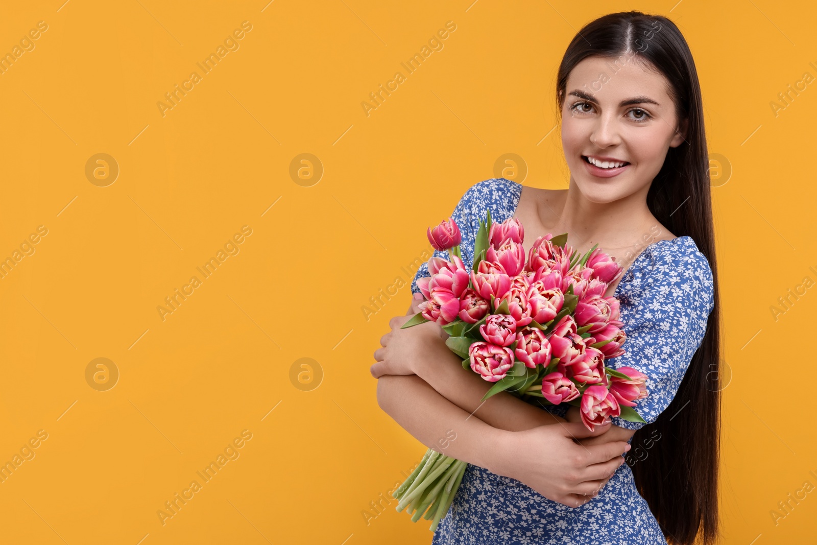 Photo of Happy young woman with beautiful bouquet on orange background. Space for text