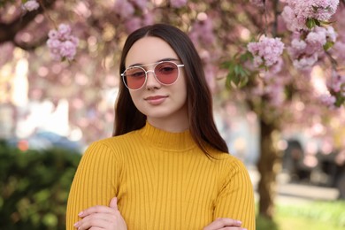 Photo of Beautiful woman in sunglasses near blossoming tree on spring day