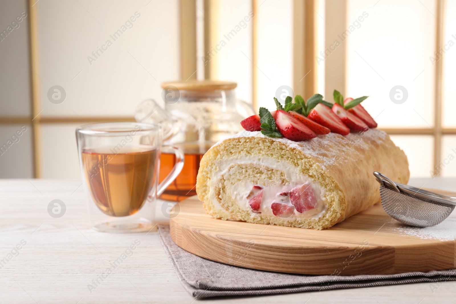 Photo of Delicious cake roll with strawberries and cream on table indoors