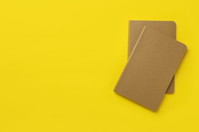 Photo of New stylish kraft planners on yellow background, top view. Space for text