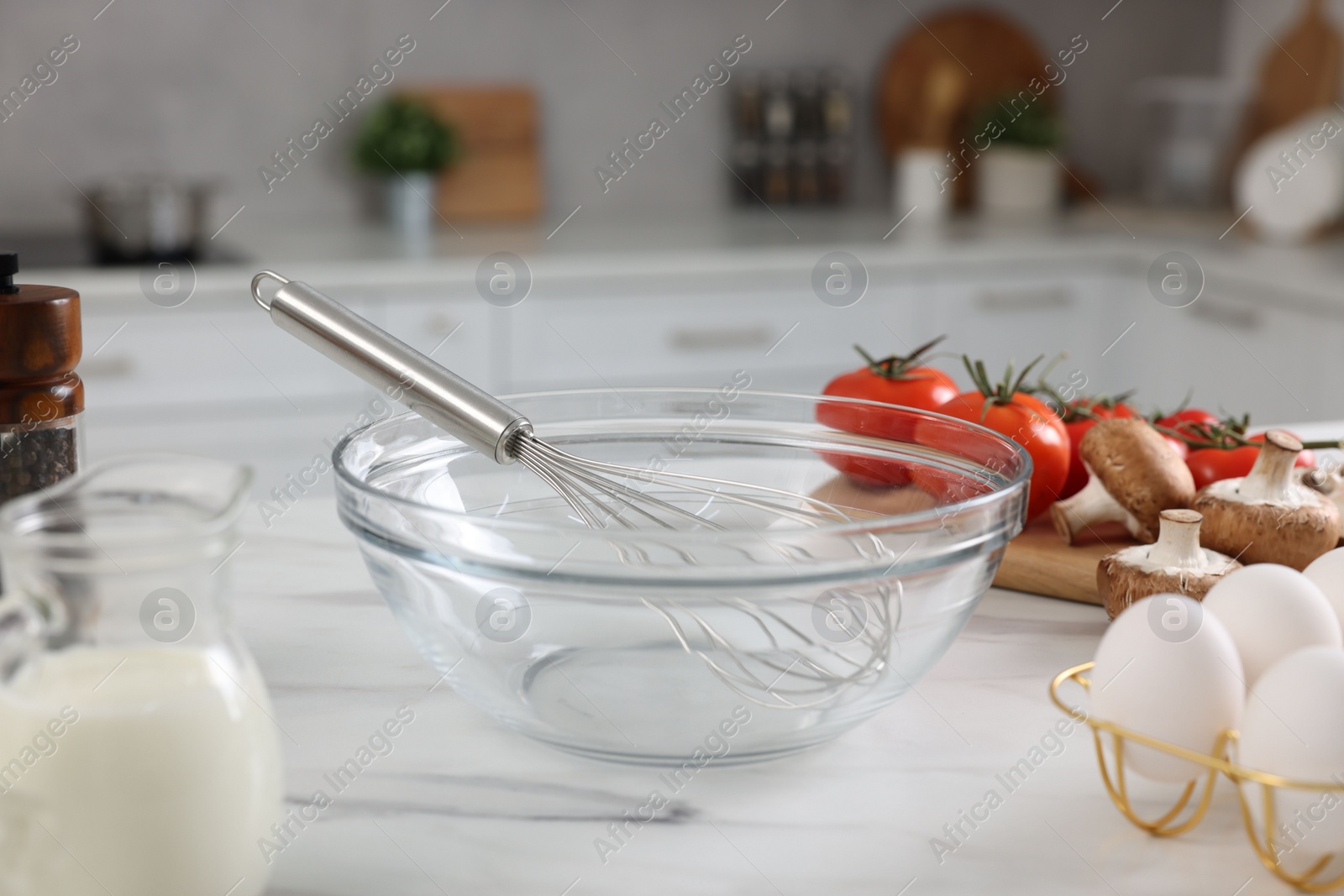 Photo of Whisk, bowl, and different ingredients on white marble table indoors