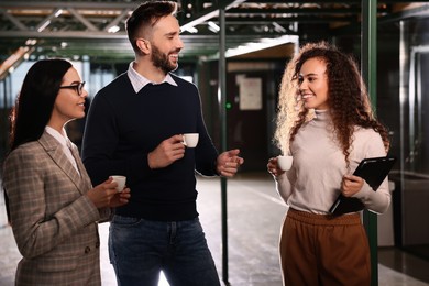 Photo of Group of coworkers talking during coffee break in office