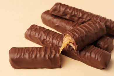 Photo of Sweet tasty chocolate bars with caramel on beige background, closeup