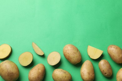 Photo of Fresh raw potatoes on green background, flat lay. Space for text