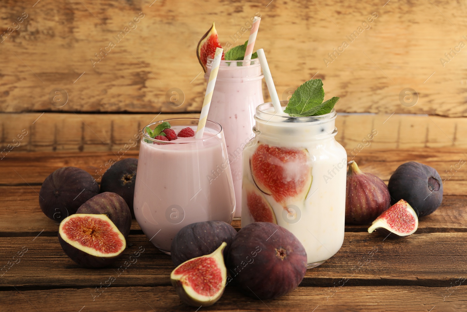 Photo of Delicious fig smoothies in glassware on wooden table