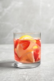 Photo of Tasty refreshing drink with strawberries and lemon on light grey table. Space for text