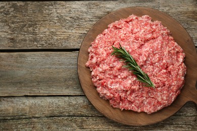 Photo of Raw fresh minced meat with rosemary on wooden table, top view. Space for text