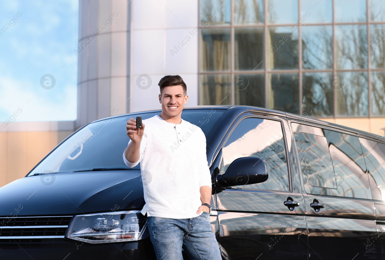 Photo of Man with key near car on city street. Buying new auto