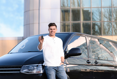 Photo of Man with key near car on city street. Buying new auto