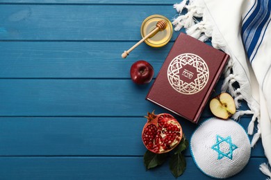 Photo of Flat lay composition with Rosh Hashanah holiday attributes on blue wooden table. Torah book with text in hebrew