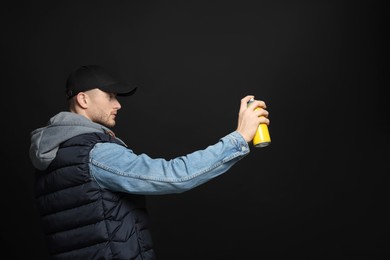 Photo of Handsome man holding used can of spray paint on black background