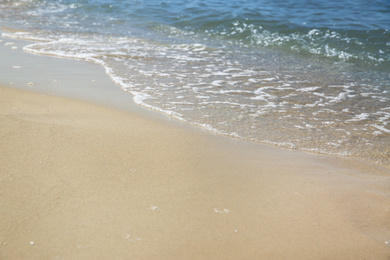 Photo of Beautiful sea waves on sandy beach, closeup