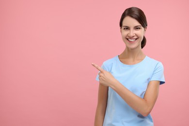 Photo of Special promotion. Happy woman pointing at something on pink background, space for text