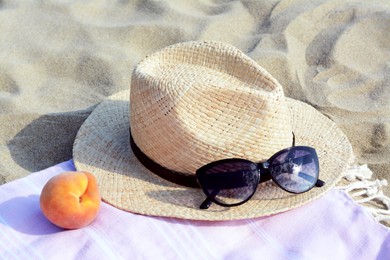 Photo of Hat with beautiful sunglasses and peach on sand