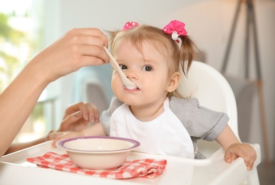 Photo of Mother feeding her cute little baby with healthy food at home