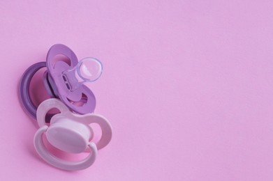 Photo of New baby pacifiers on pink background, flat lay. Space for text