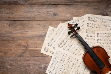 Violin and music sheets on wooden table, top view. Space for text