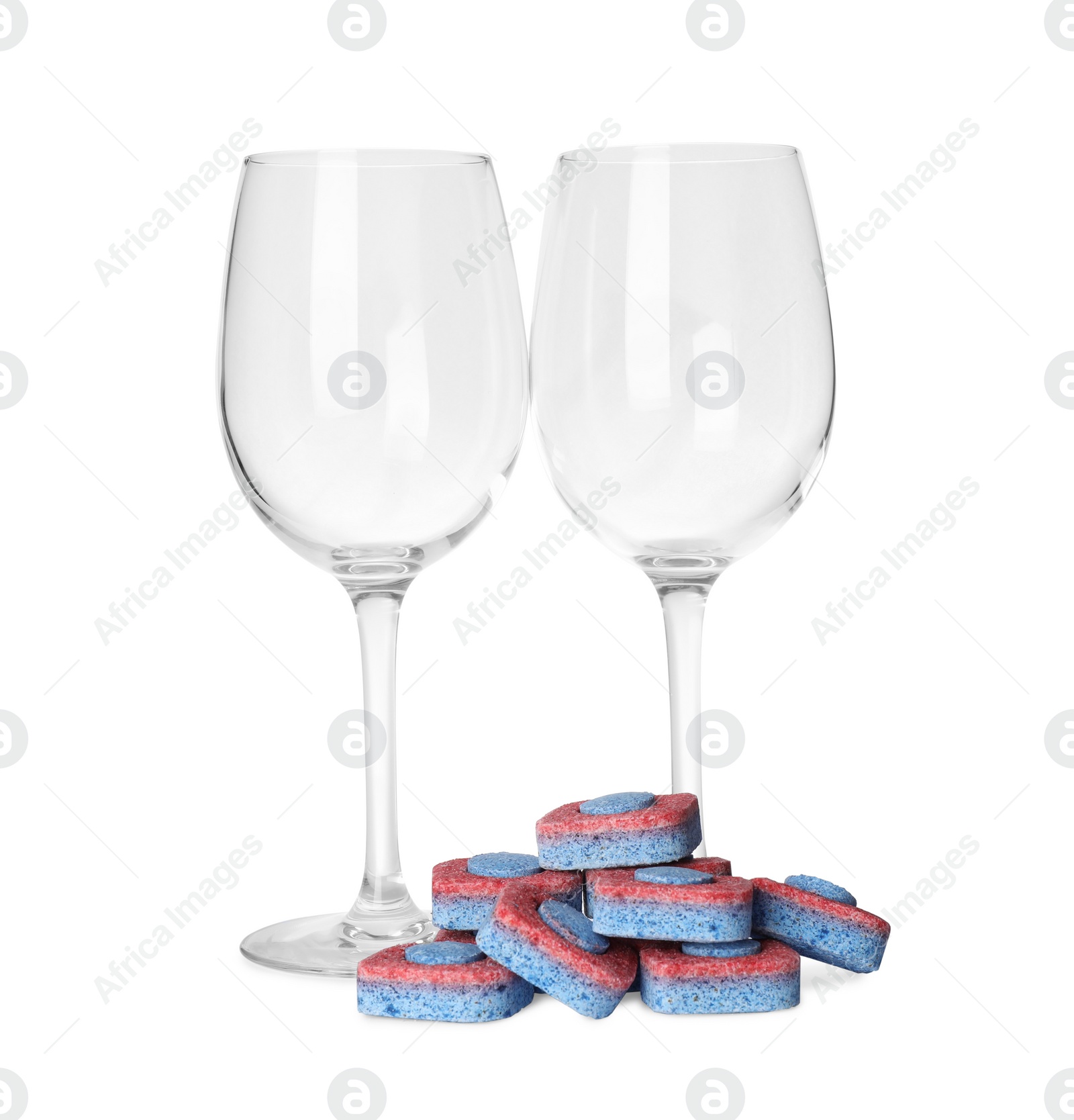 Photo of Wineglasses and many dishwasher detergent tablets on white background