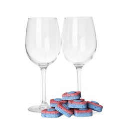 Photo of Wineglasses and many dishwasher detergent tablets on white background