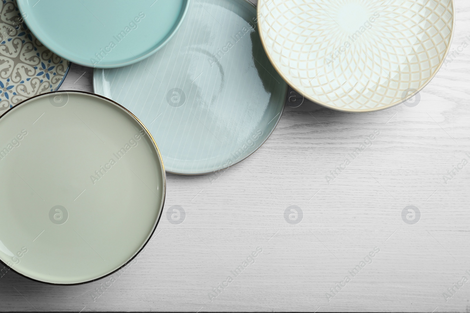 Photo of Beautiful plates on white wooden table, flat lay. Space for text