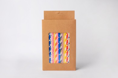 Box with many paper drinking straws on light grey background