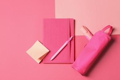 Photo of Bright notebook and case with other stationery on pink background, flat lay