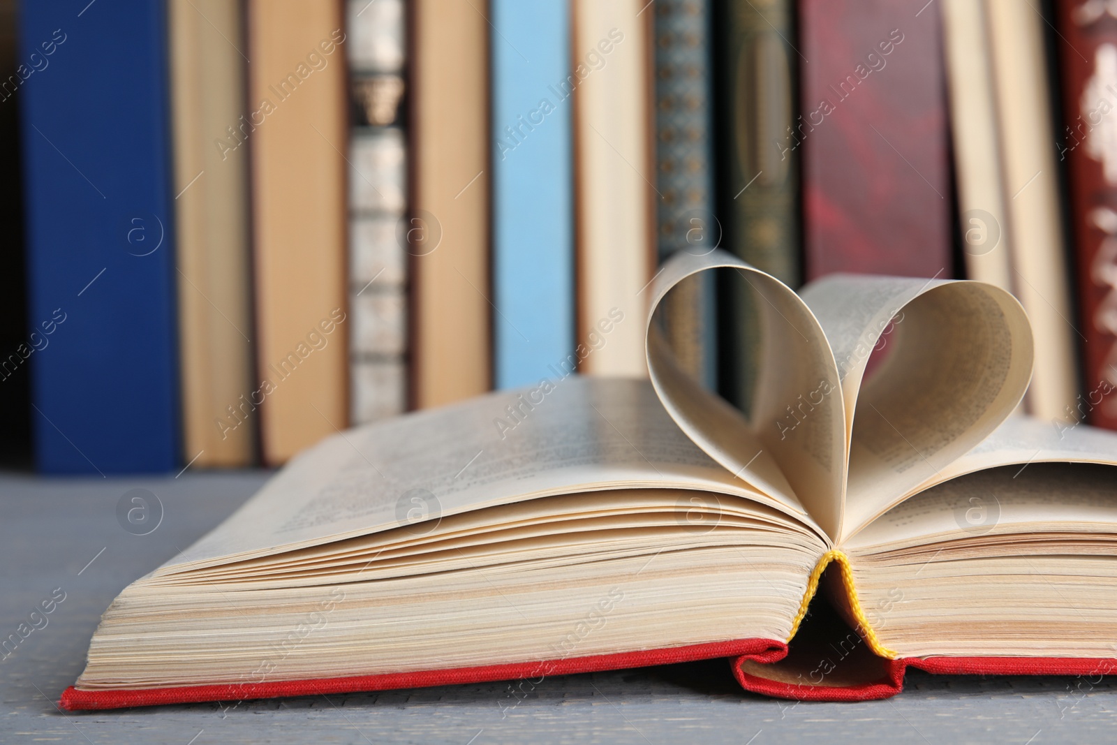 Photo of Open hardcover book on grey wooden table, closeup
