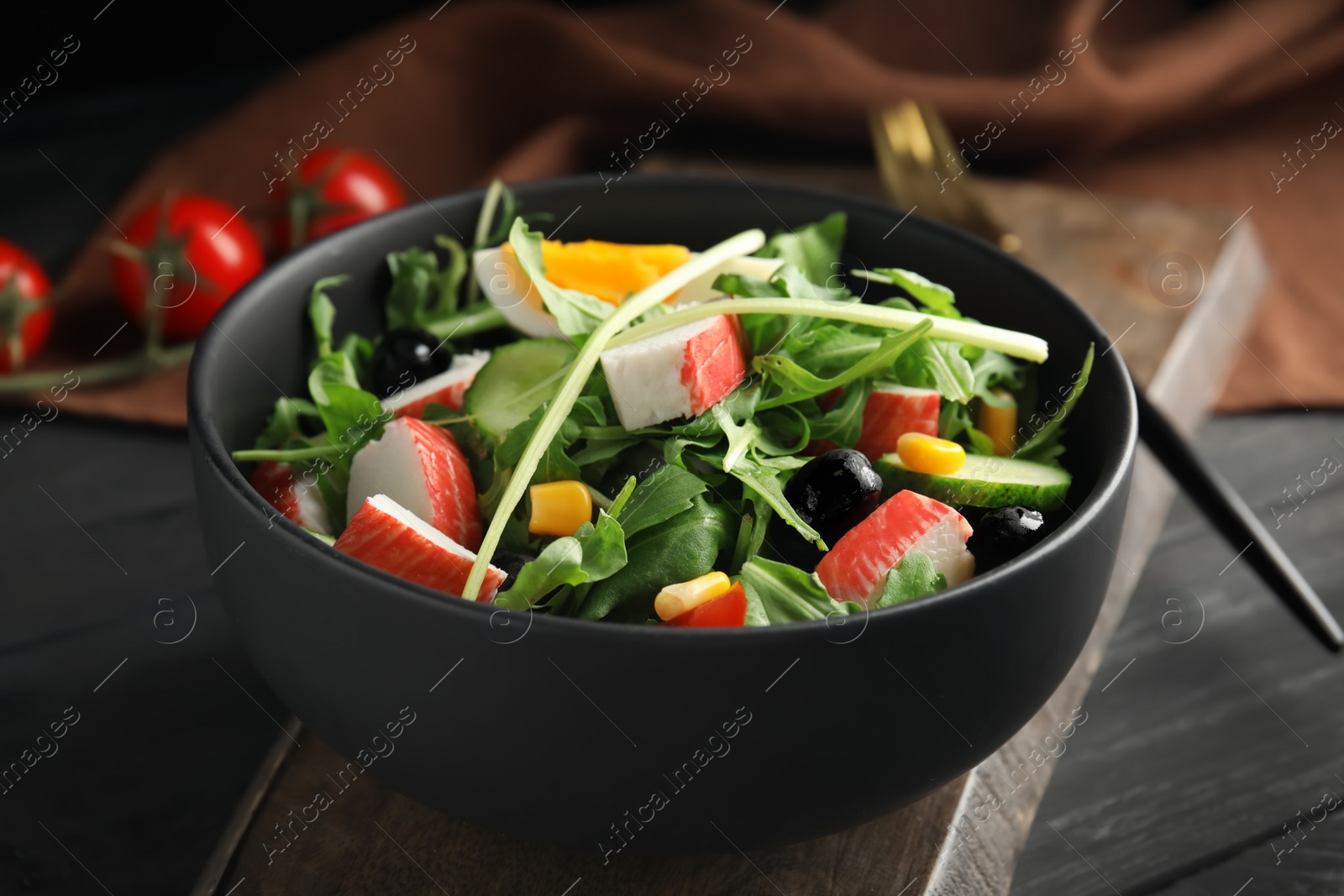 Photo of Tasty crab stick salad served on grey wooden table, closeup