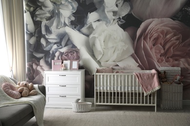 Baby room interior with stylish crib and floral wallpaper