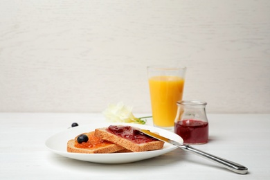 Photo of Toasts with jam and glass of juice on table