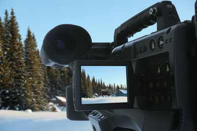 Recording beautiful view of snowy forest on professional video camera