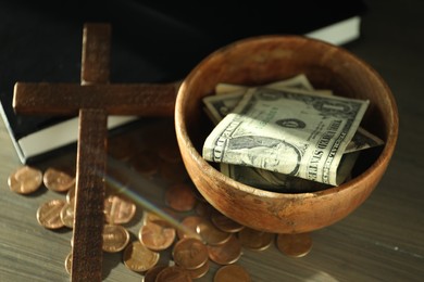 Donate and give concept. Bowl with coins, dollar banknotes, cross and Bible on wooden table