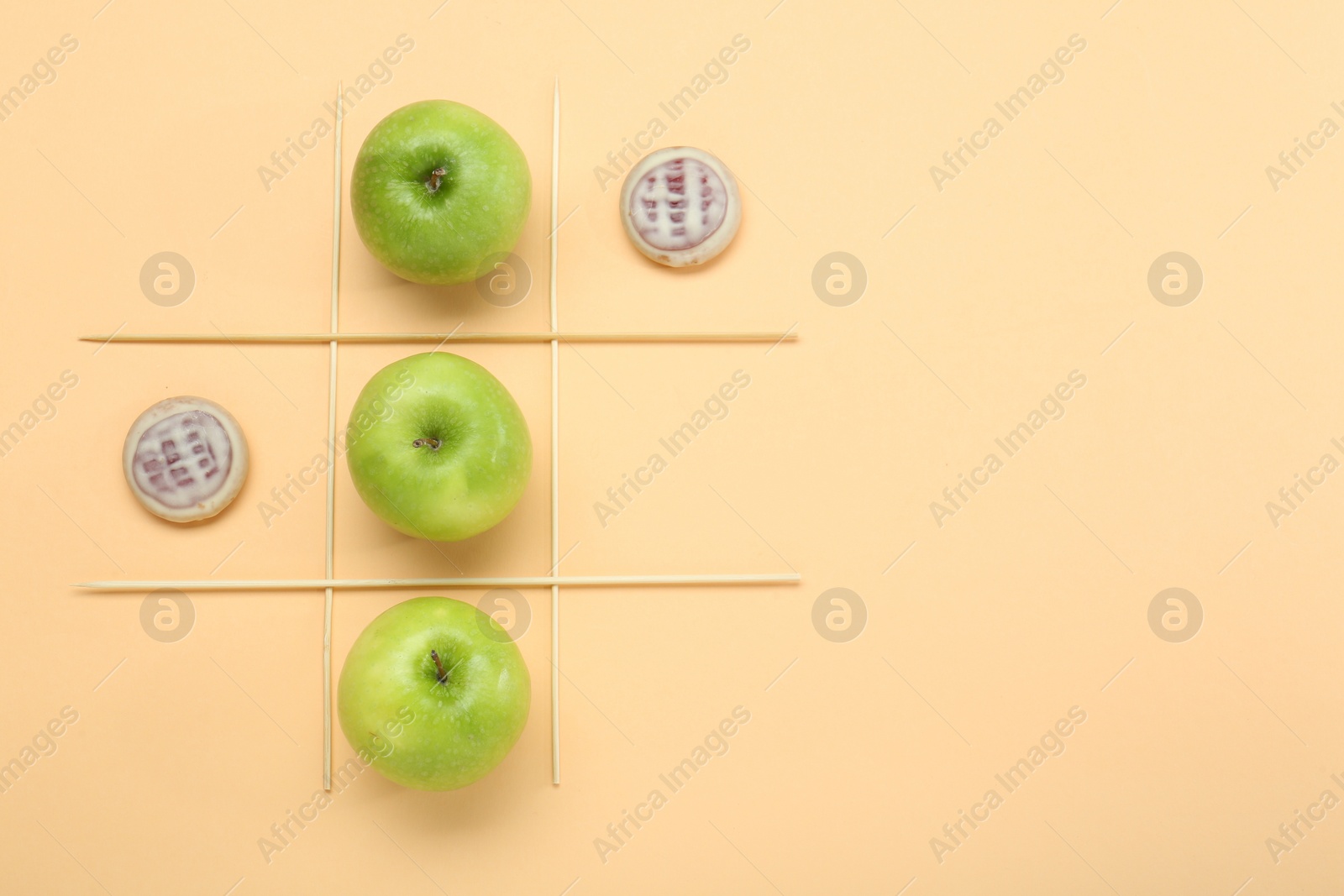 Photo of Tic tac toe game made with apples and cookies on beige background, top view