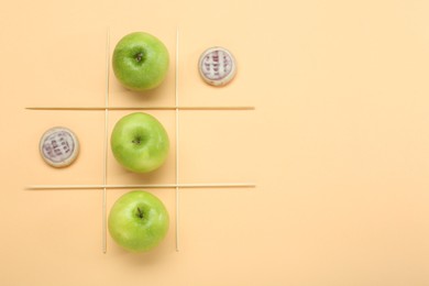 Tic tac toe game made with apples and cookies on beige background, top view