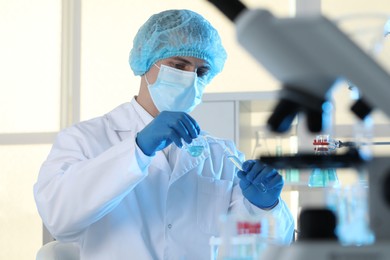 Scientist pouring sample into test tube in laboratory. Medical research