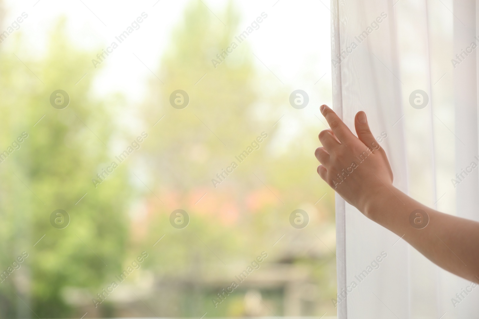 Photo of Woman opening curtain indoors, closeup. Space for text