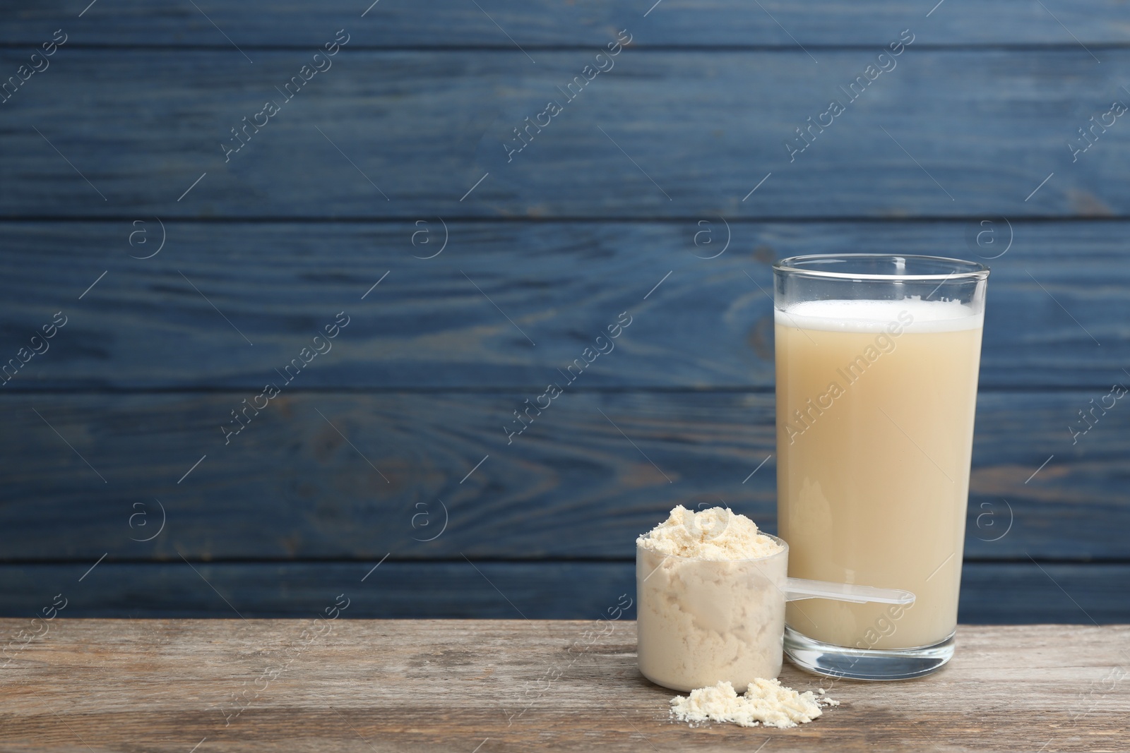 Photo of Protein shake and powder on wooden table, space for text