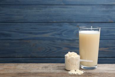 Protein shake and powder on wooden table, space for text